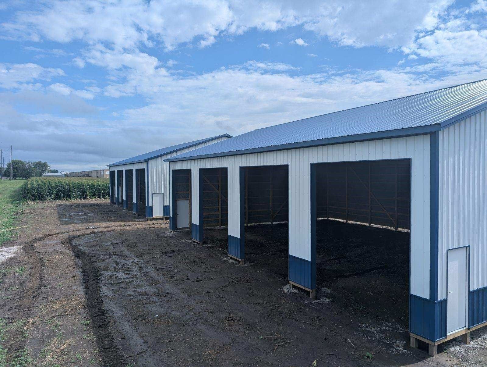 White post-frame shop with two overhead doors and a walk door
