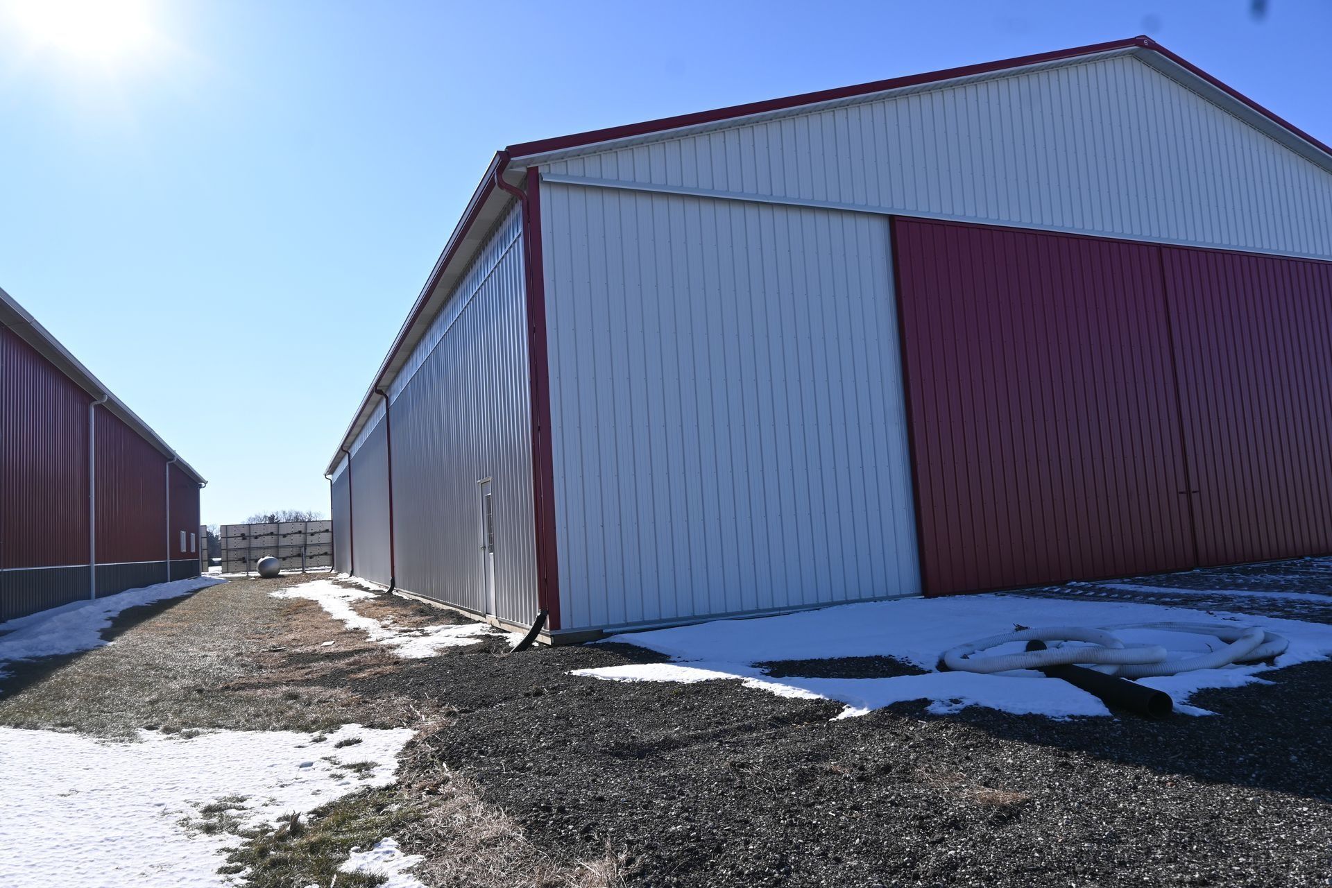 Large white steel-sided building with a red overhead door